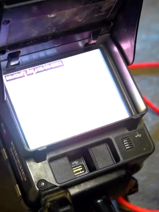 A sewer inspection monitor on the floor showing the inside of a pipe, camera reel alongside
