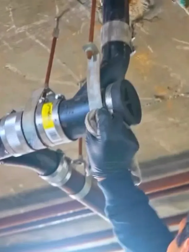 A technician breaking out concrete floor inside a plastic containment to reach a failed drain line